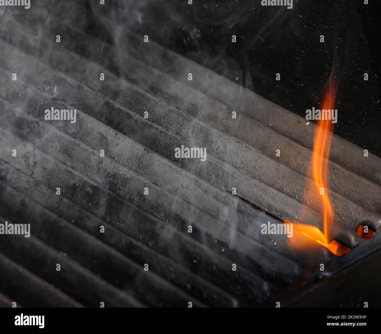 Close up empty cast iron metal BBQ grill grate with fire flames and