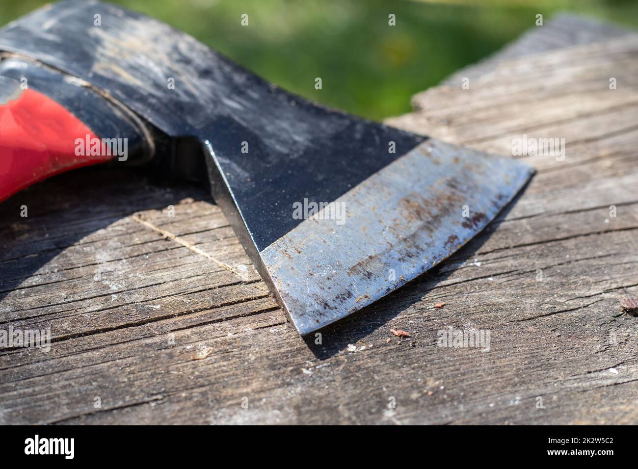 A sharp ax with an ergonomic rubberized handle on a wooden background. The ax is intended for rough, rough processing of wood. Has a forged heat treated carbon steel wedge. Stock Photo