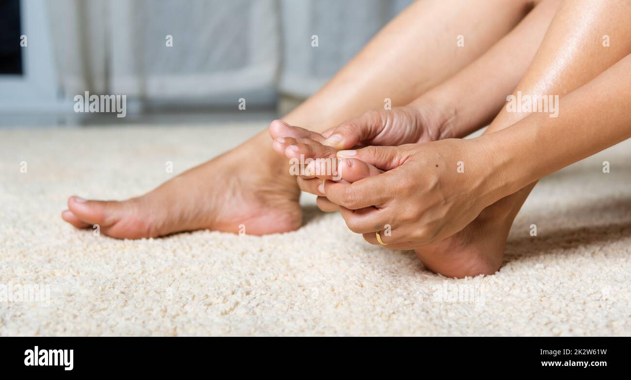 Asian woman holds her toe injury feeling pain her foot at home Stock Photo