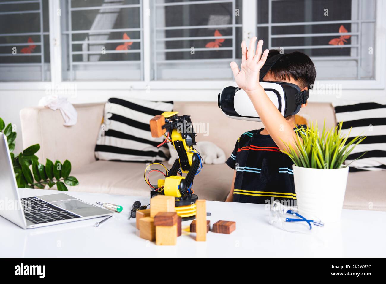 Asian kid boy using VR glasses on robotic arm in workshop Stock Photo