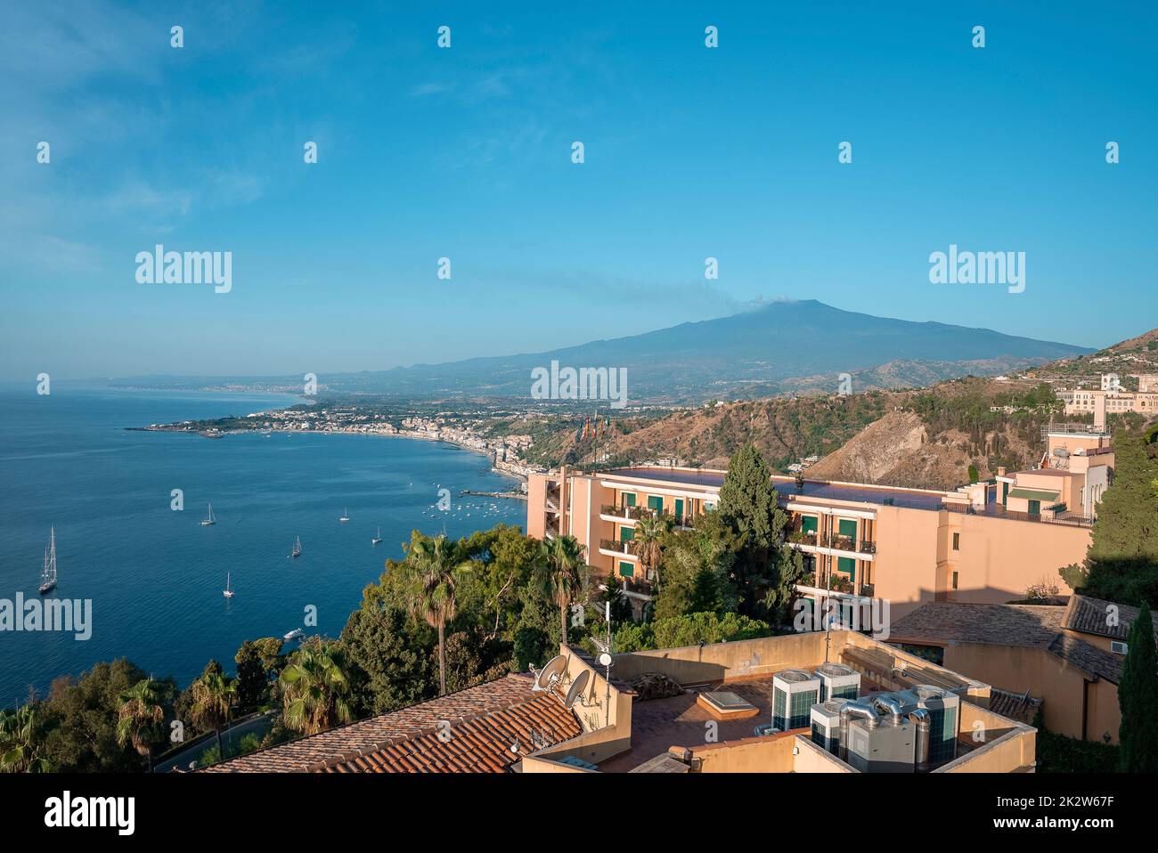 Scenic view of Hotel Elios and Etna Volcano by seascape with sky in background Stock Photo
