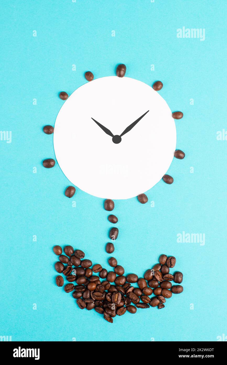 Alarm clock flower made from coffee beans, wake up in the morning, having a deadline, time for a break, minimalistic concept, blue background Stock Photo