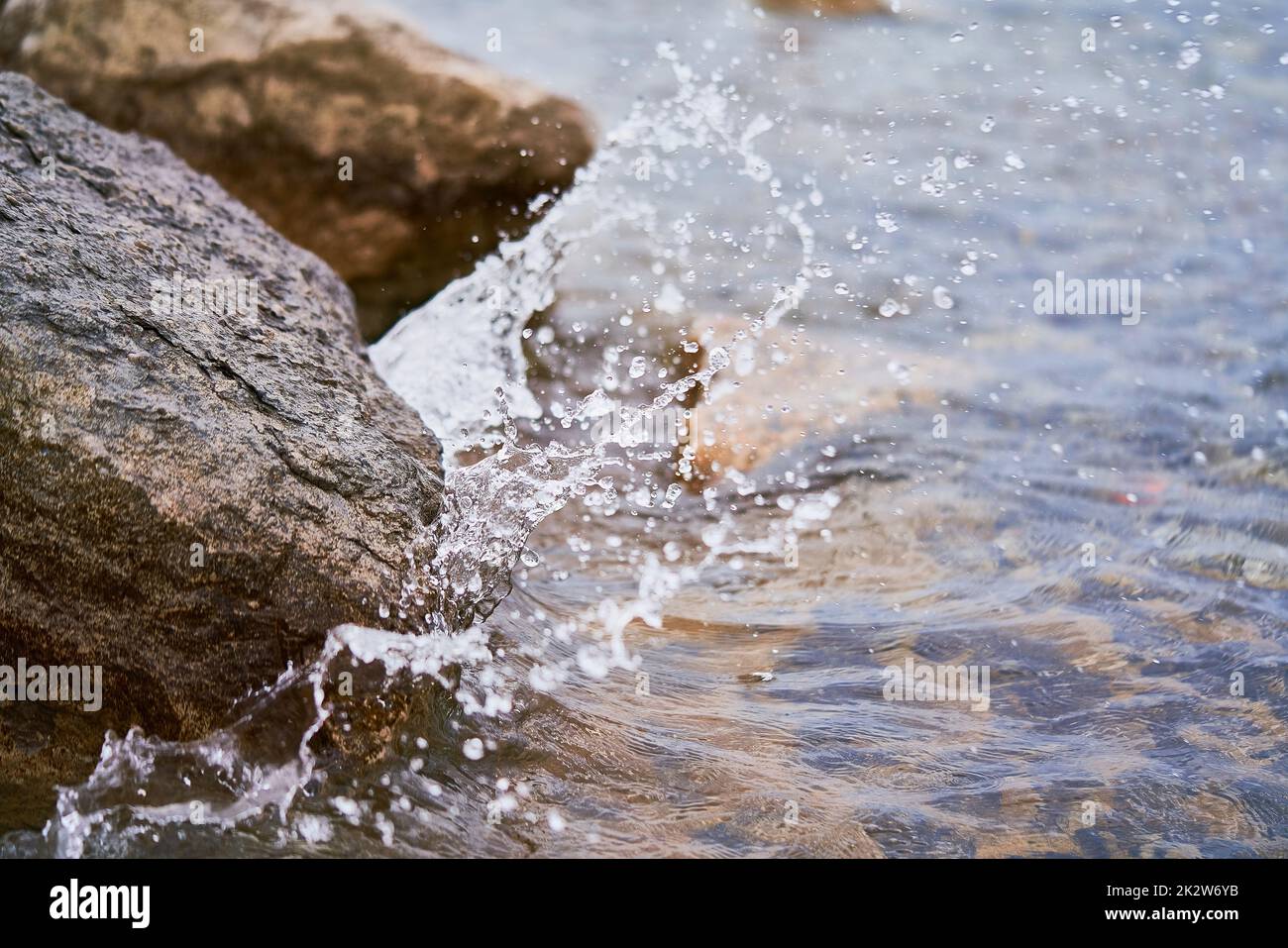 A closeup shot of a wave of the lake splashing on the rocks in the ...