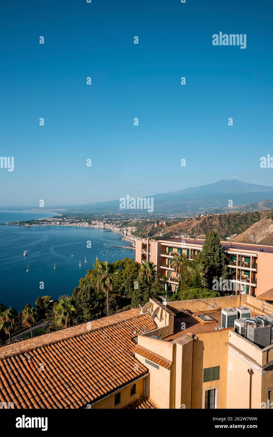 Idyllic scenery of Hotel Elios and Mount Etna by seascape with sky in background Stock Photo