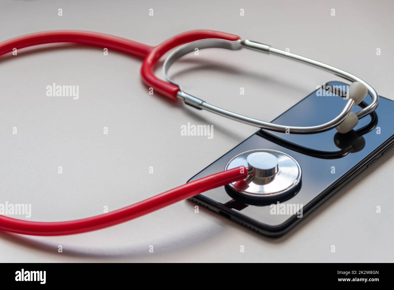 Red stethoscope on black smartphone represents health records and digital patient records with mobile devices for digital doctors and digital diagnostic treatment with modern equipment and technology Stock Photo