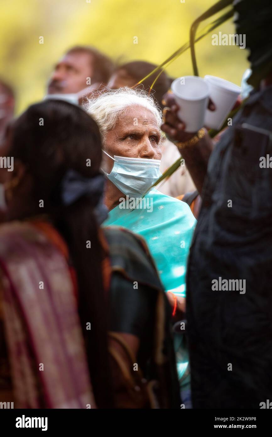 A vertical shot of an authentic senior Indian female in a traditional costume wearing a mask Stock Photo