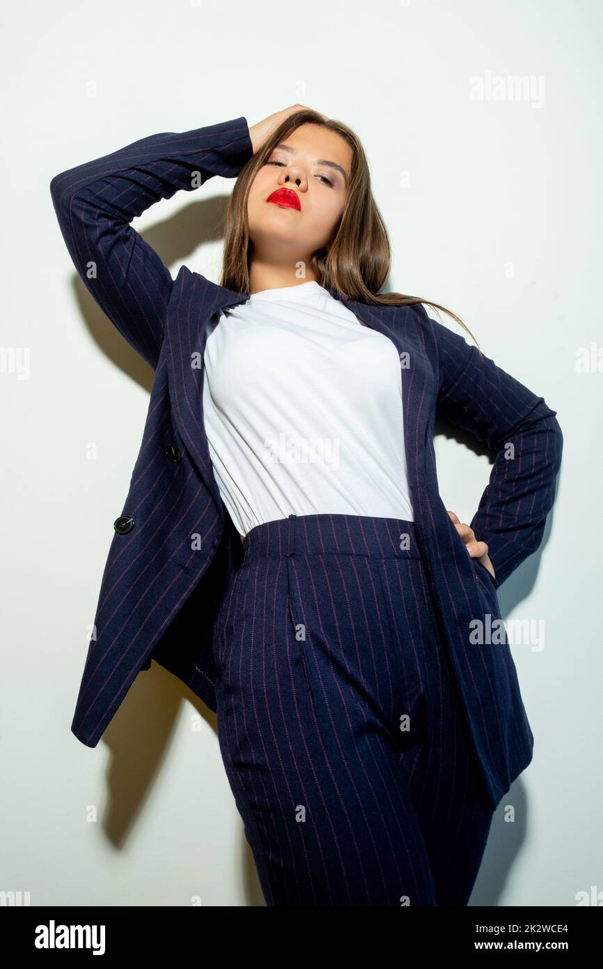 Successful woman lifestyle. Business fashion. Female individuality. Confident stylish lady in blue suit standing posing isolated on light neutral wall Stock Photo