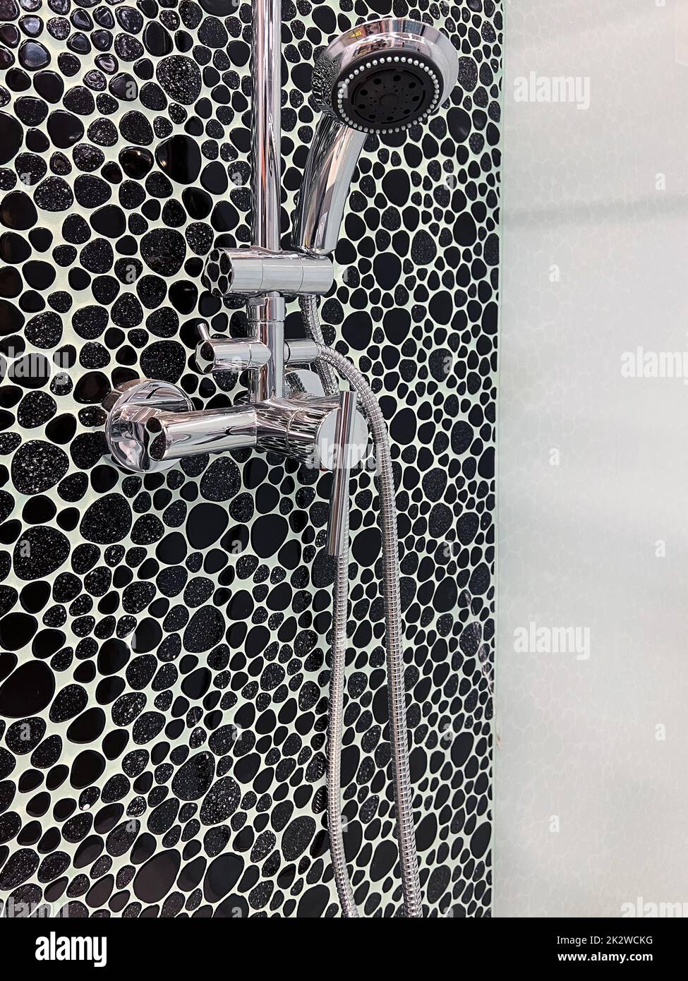 shower cabin with chrome head and faucet decorated with black pebbles