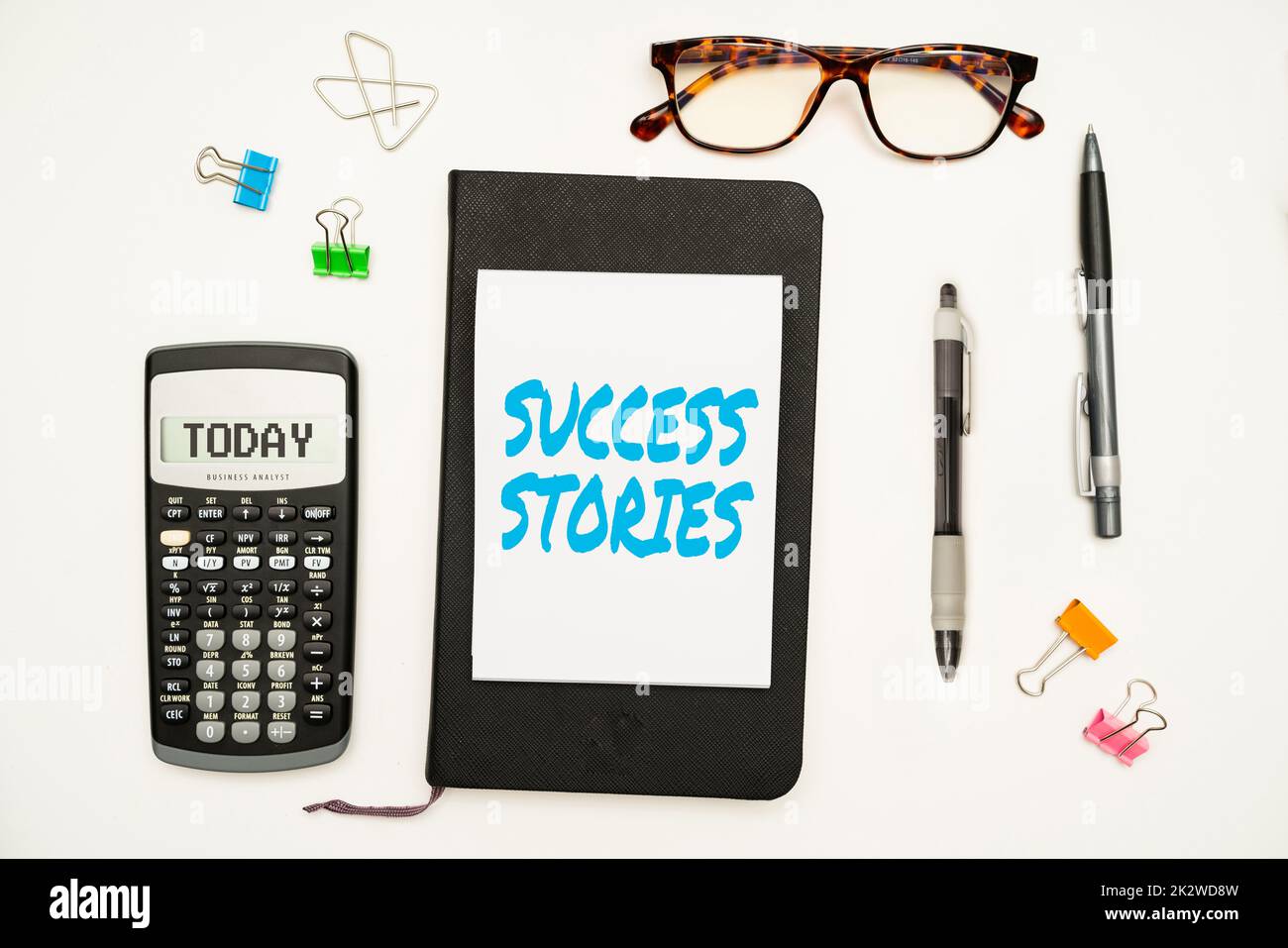 Writing displaying text Success Stories. Business overview life of rule models from how he started to his death Office Supplies Over Desk With Keyboard And Glasses And Coffee Cup For Working Stock Photo