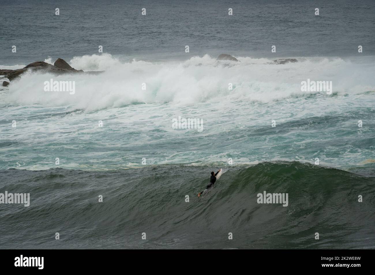 A scenic shot of a surfer catching a large wave at Wedding Cake Island, Sydney Stock Photo