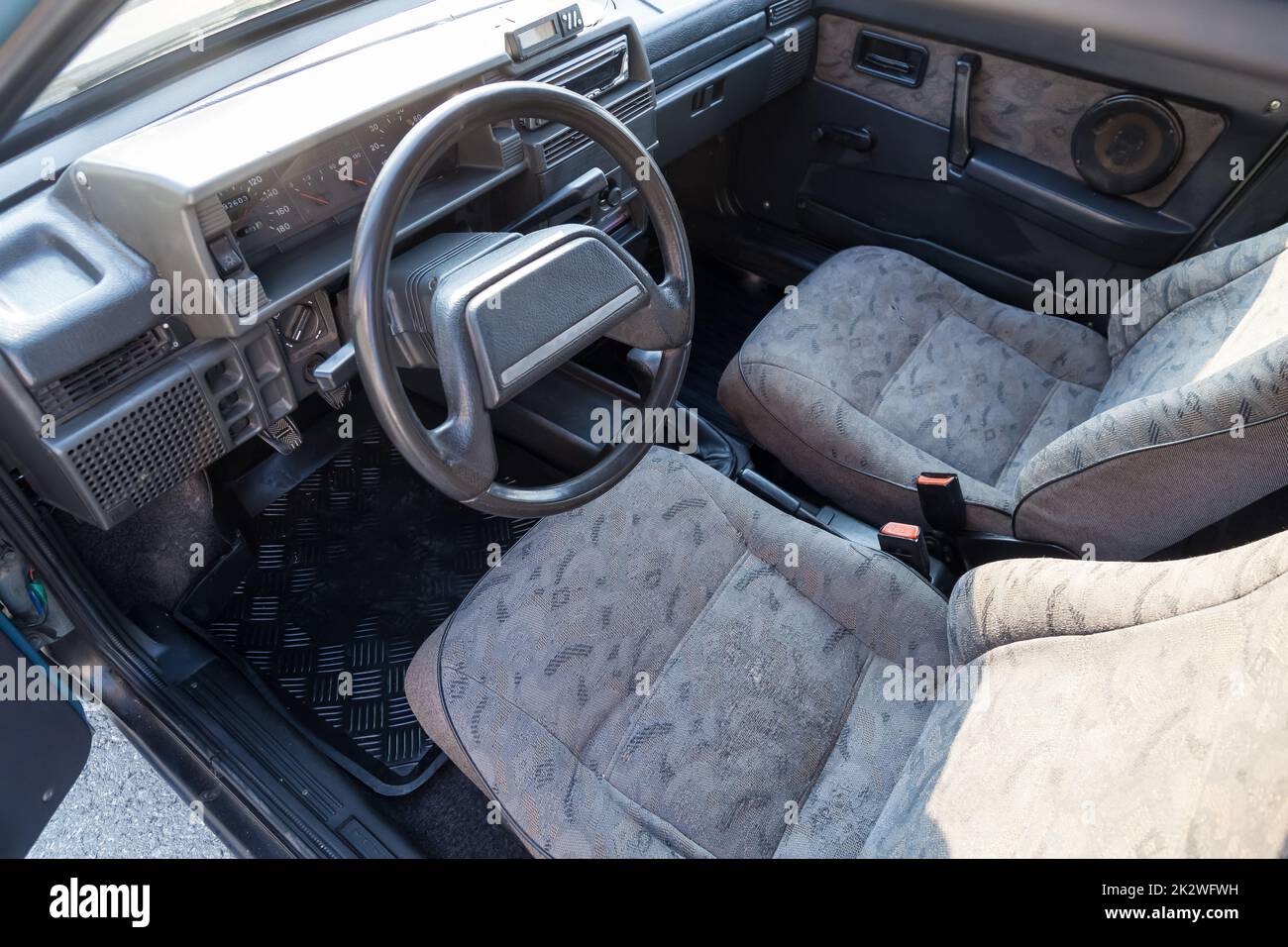 view through the reclined seat with a gray cloth and belt on the front panel of black plastic and the driver's seat in the old car Stock Photo