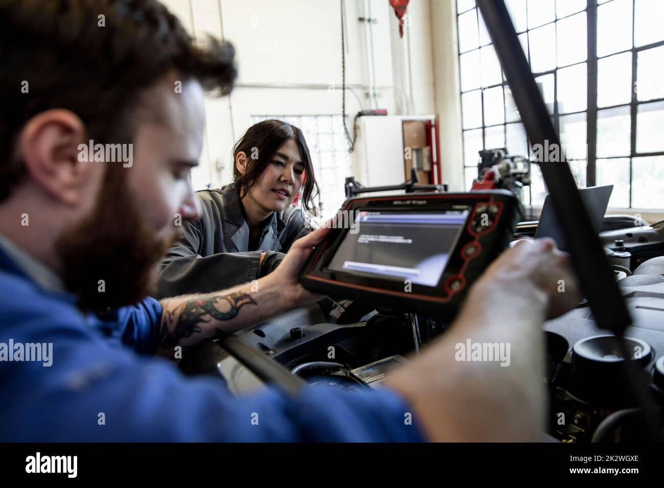 Auto mechanics performing diagnostic test on SUV engine in garage Stock