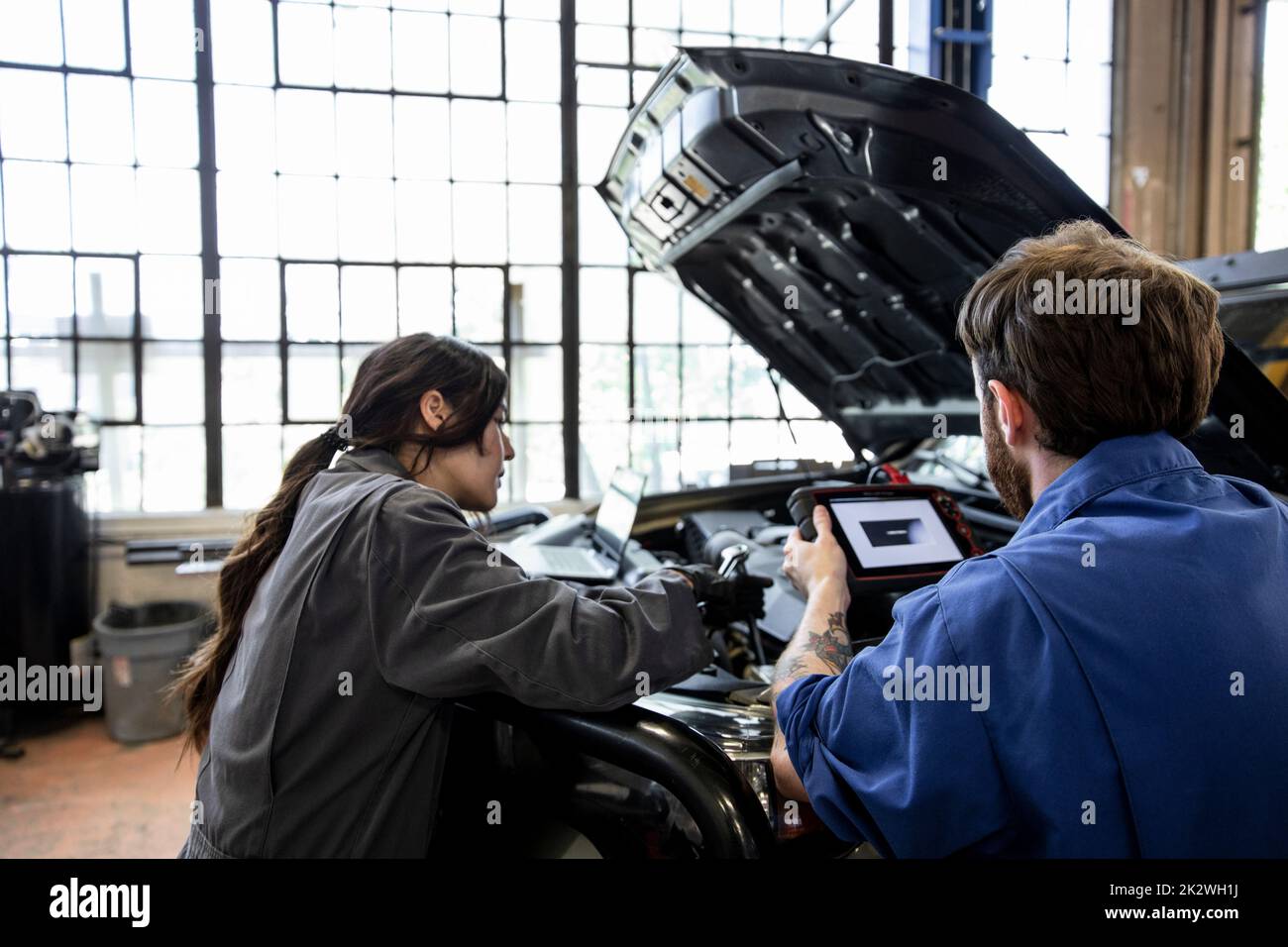 Auto mechanics doing diagnostic test on modified SUV engine in garage