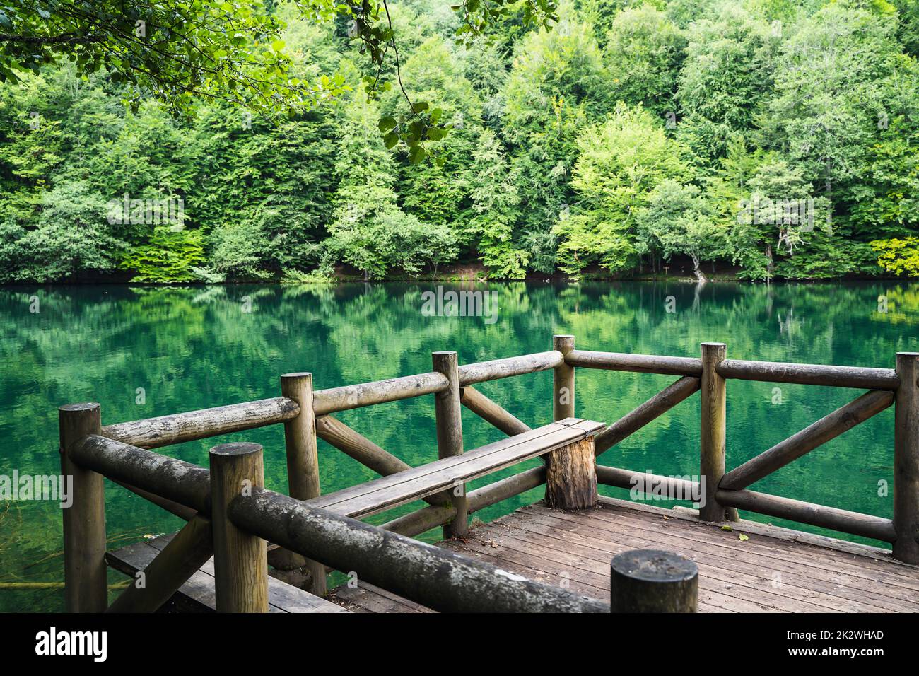 closeup of wooden dock with sitting bench on a lake surrounded by beautiful green forest in Yedigoller National Park Turkey with no people Stock Photo