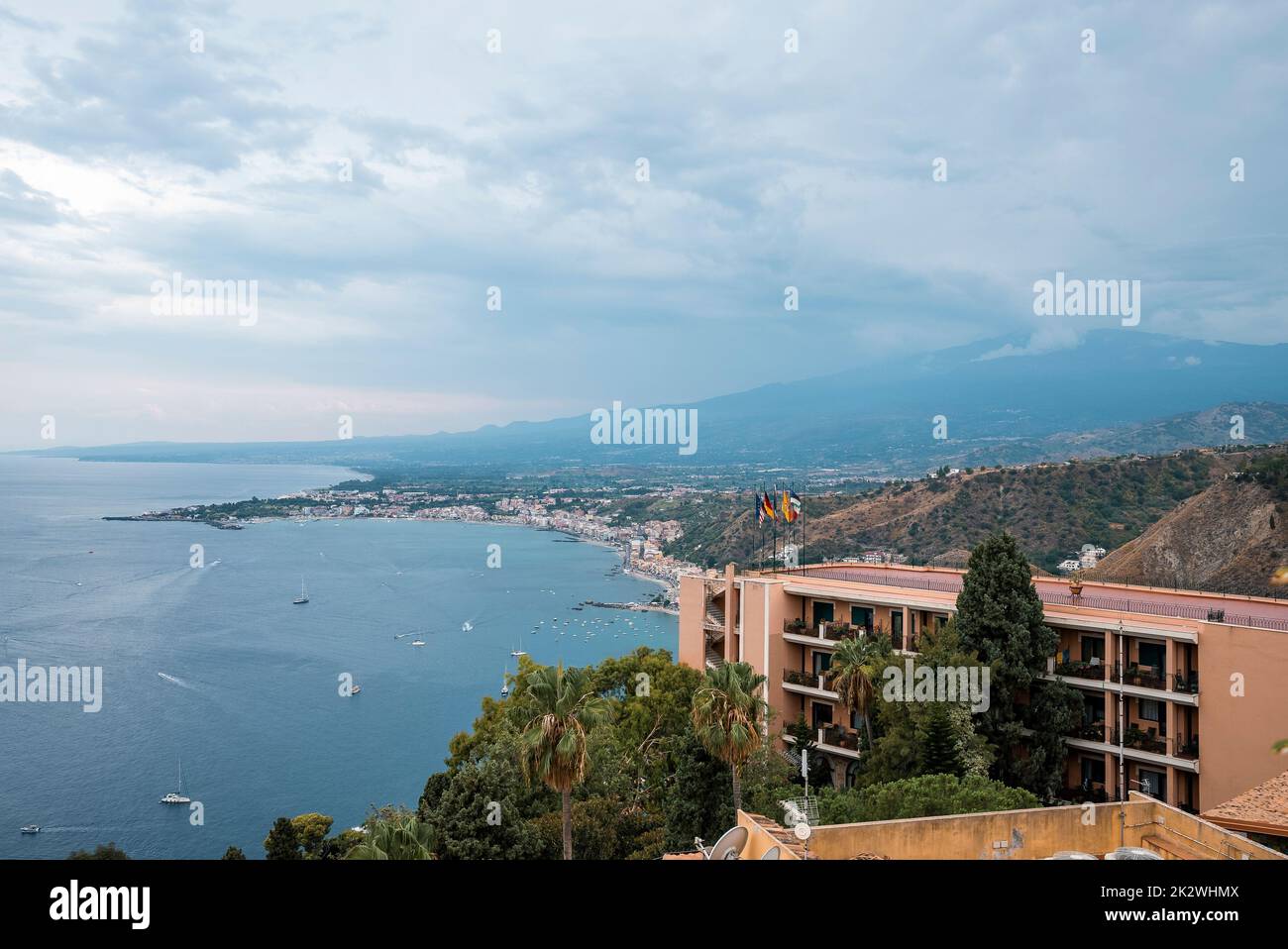 Idyllic view of Hotel Elios and Mount Etna by seascape with sky in background Stock Photo