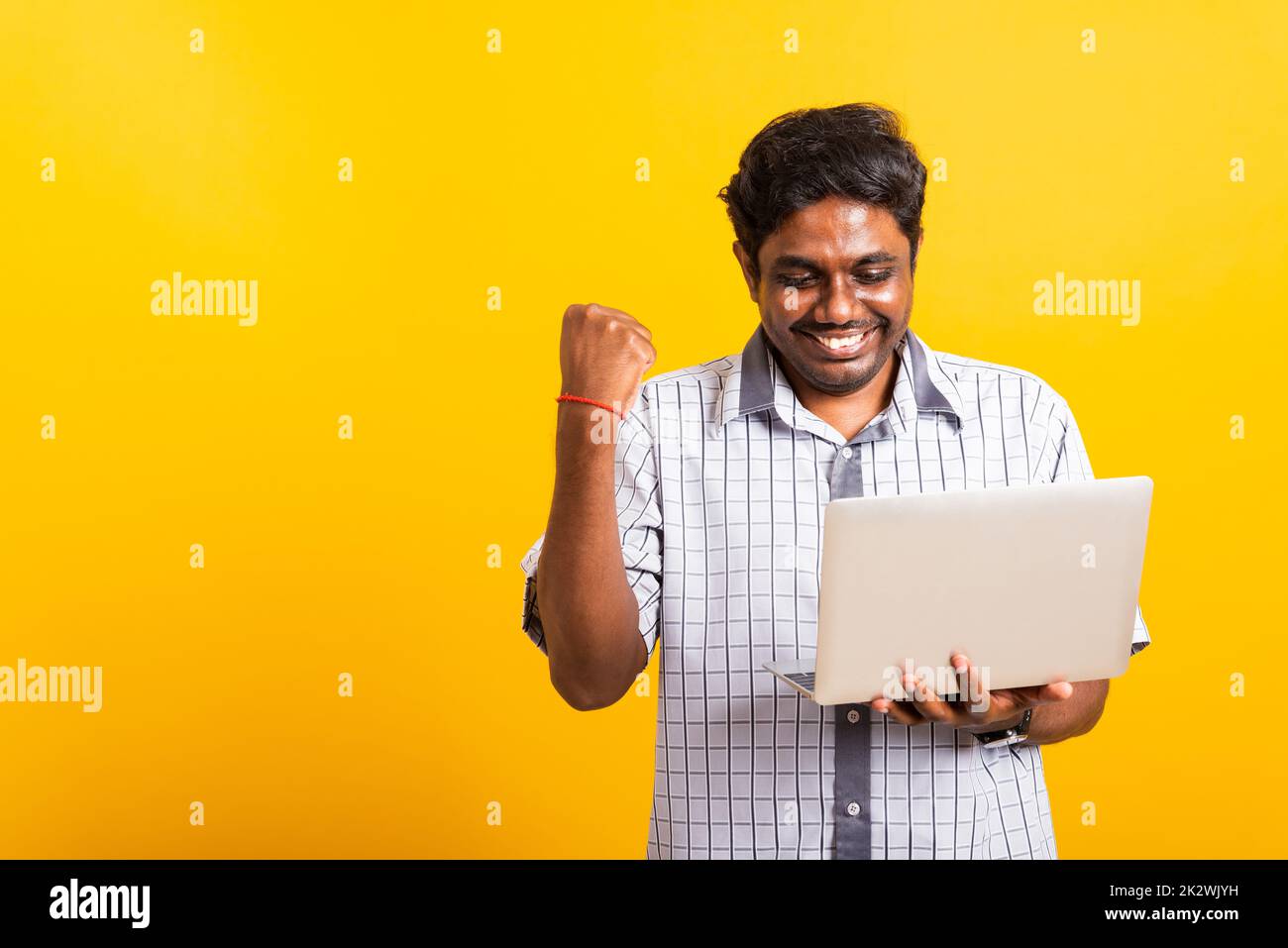 black man excited holding laptop computer clenching fists and raising a hand for winner Stock Photo