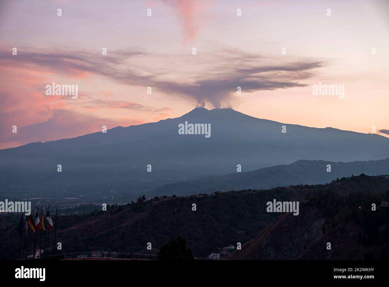 Smoke emitting from volcanic Mount Etna with luxurious Hotel Elios in foreground Stock Photo