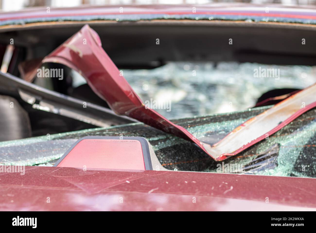 A car after an accident with a broken rear window. Broken window in a vehicle with a rear brake light. Interior wreckage, detailed close-up view of a damaged modern car. Stock Photo