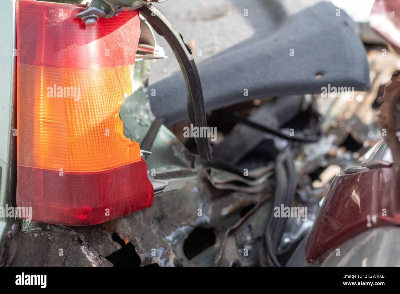 A red and orange broken glass lamp on a car as a result of a violent collision. Broken rear headlight close-up due to a car accident or careless driving. Insured event, safe driving concept. Stock Photo
