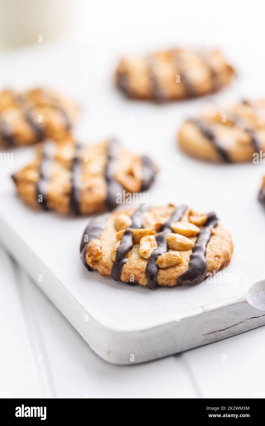 Chip cookies with peanuts and chocolate strips on white table. Stock Photo