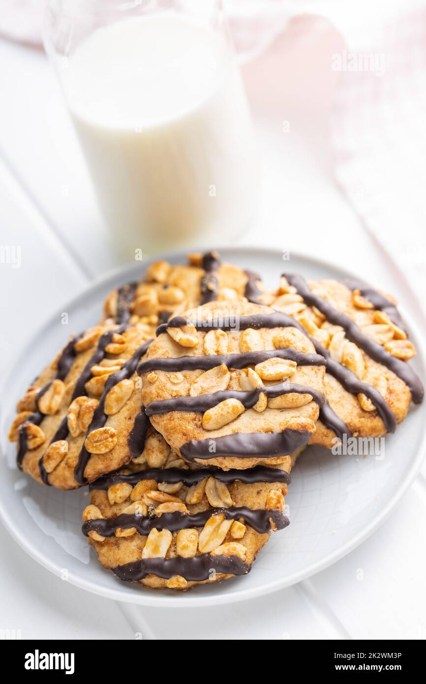 Chip cookies with peanuts and chocolate strips on white table. Stock Photo
