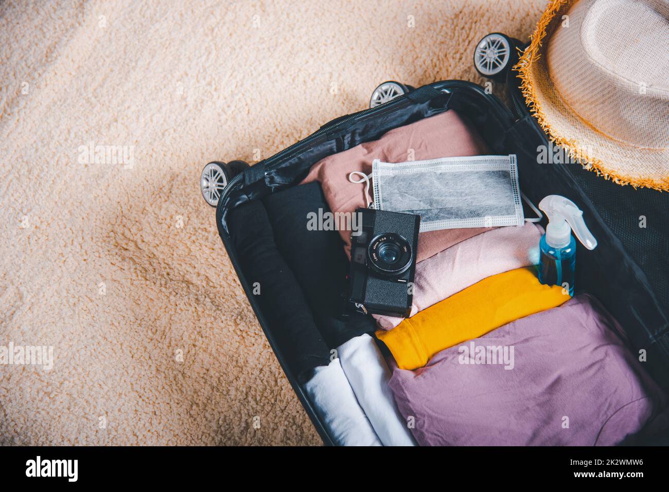 Open suitcase with traveler belongings clothes and accessories of things ready packing to be taken on summer holiday Stock Photo