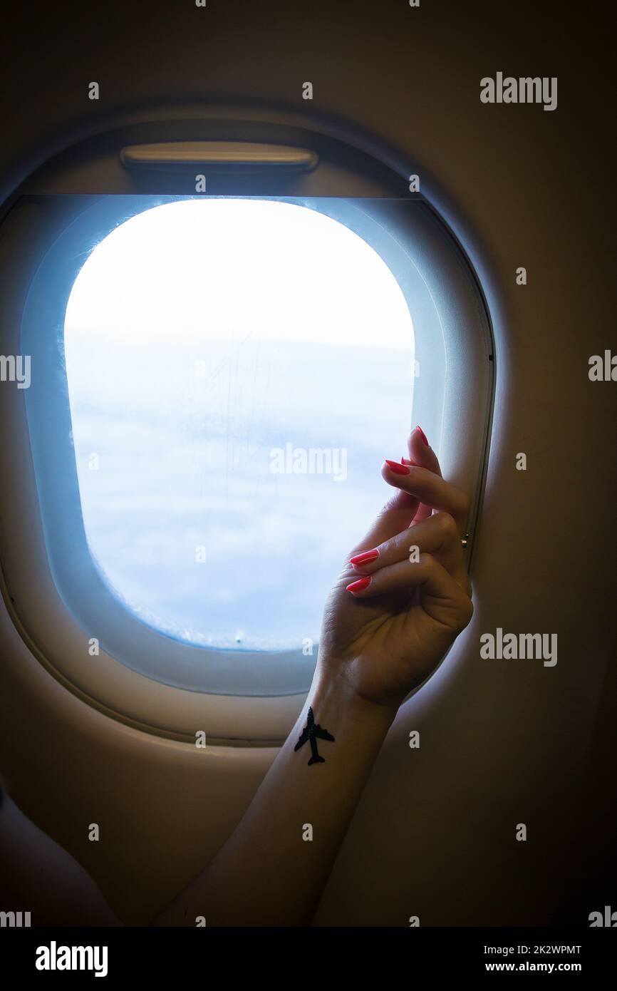 beautiful view from the airplane window on the air clouds, hand of a girl with a tattoo Stock Photo