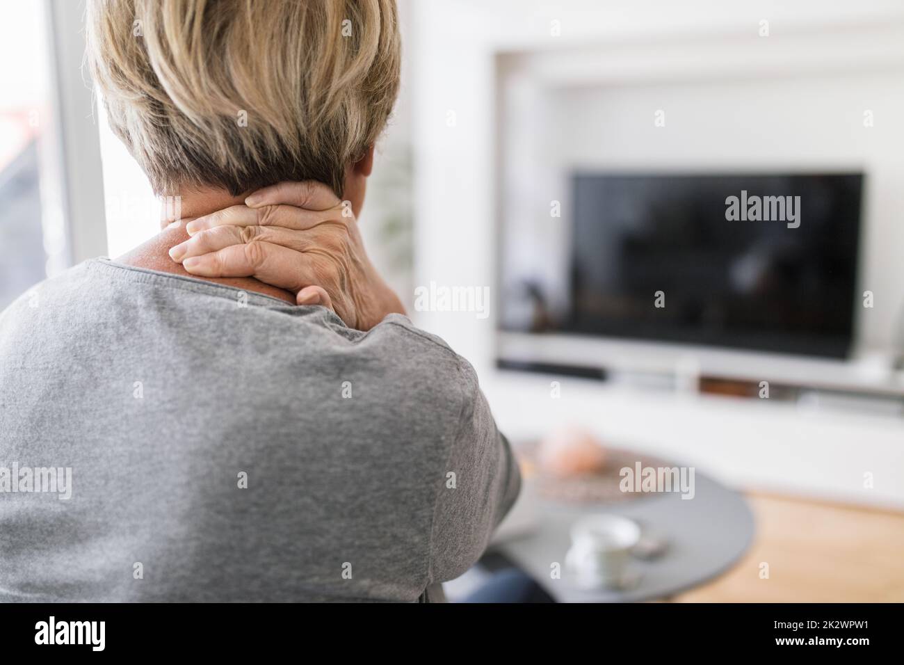Senior woman in living room with neck pain Stock Photo Alamy