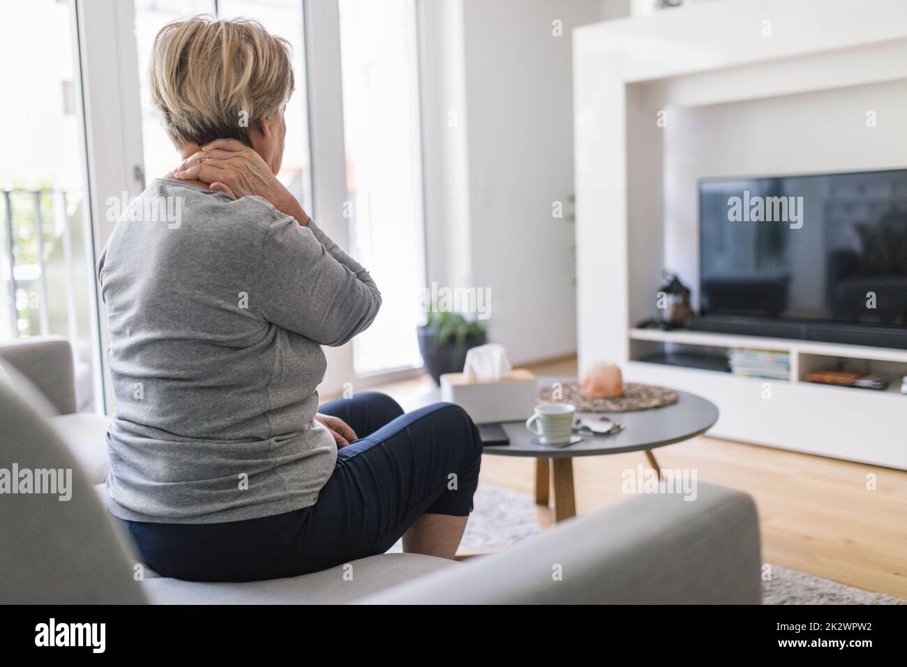 Senior woman in living room with neck pain Stock Photo Alamy