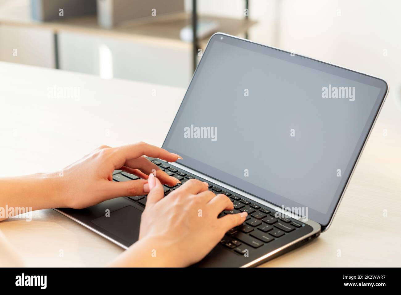 Freelance work. Remote job. Online communication. Business correspondence. Female blogger hands typing on laptop with blank black screen at light offi Stock Photo