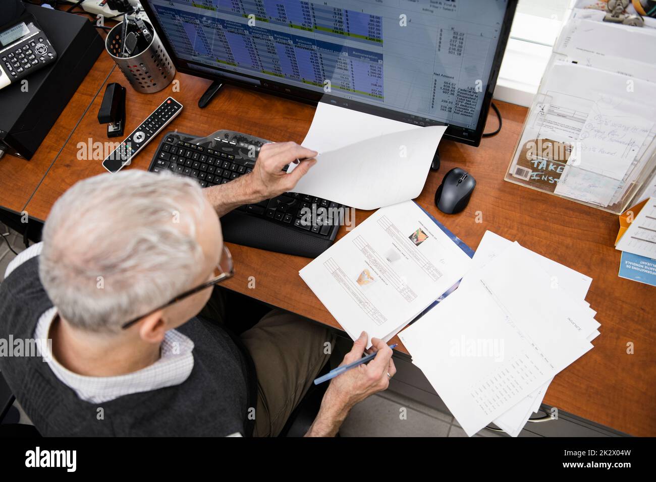 Male business owner reviewing purchase order paperwork in office Stock Photo
