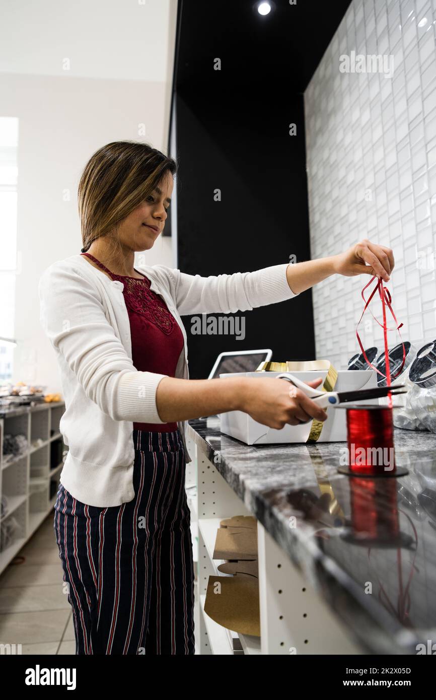 Female bakery owner cutting ribbon for pastry box Stock Photo Alamy