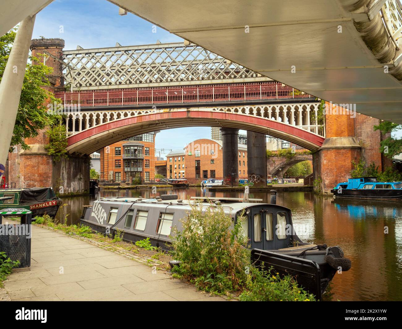 Narrowboat moored below Merchant's Bridge on the Bridgewater Canal with the railway bridge and Castlehill Viaduct behind. Manchester Stock Photo