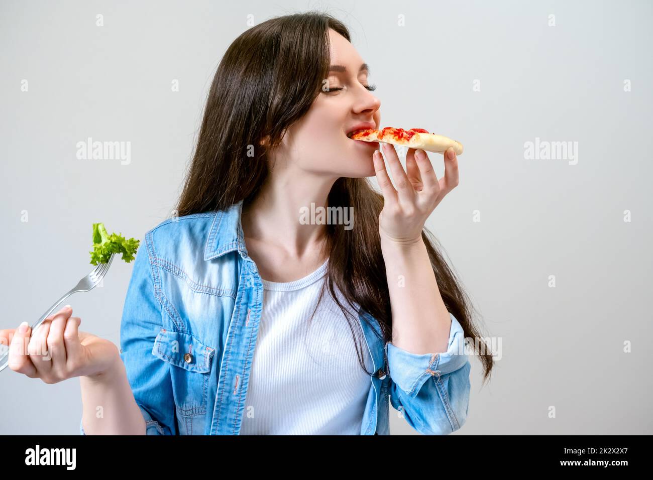 Young beautiful woman breaks the diet, but happy eats pizza instead of salad Stock Photo