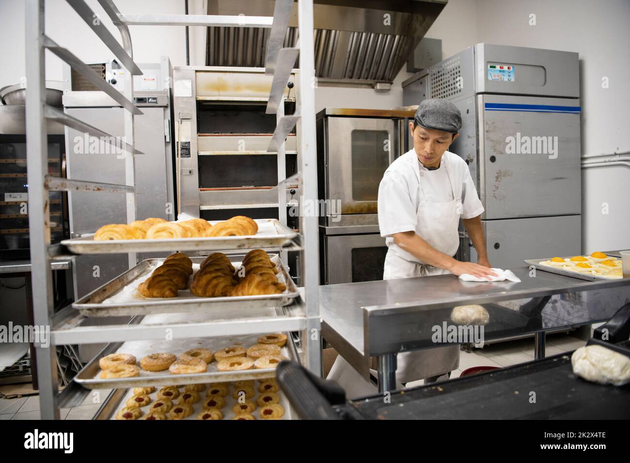 Male baker preparing French pastries in commercial bakery kitchen Stock