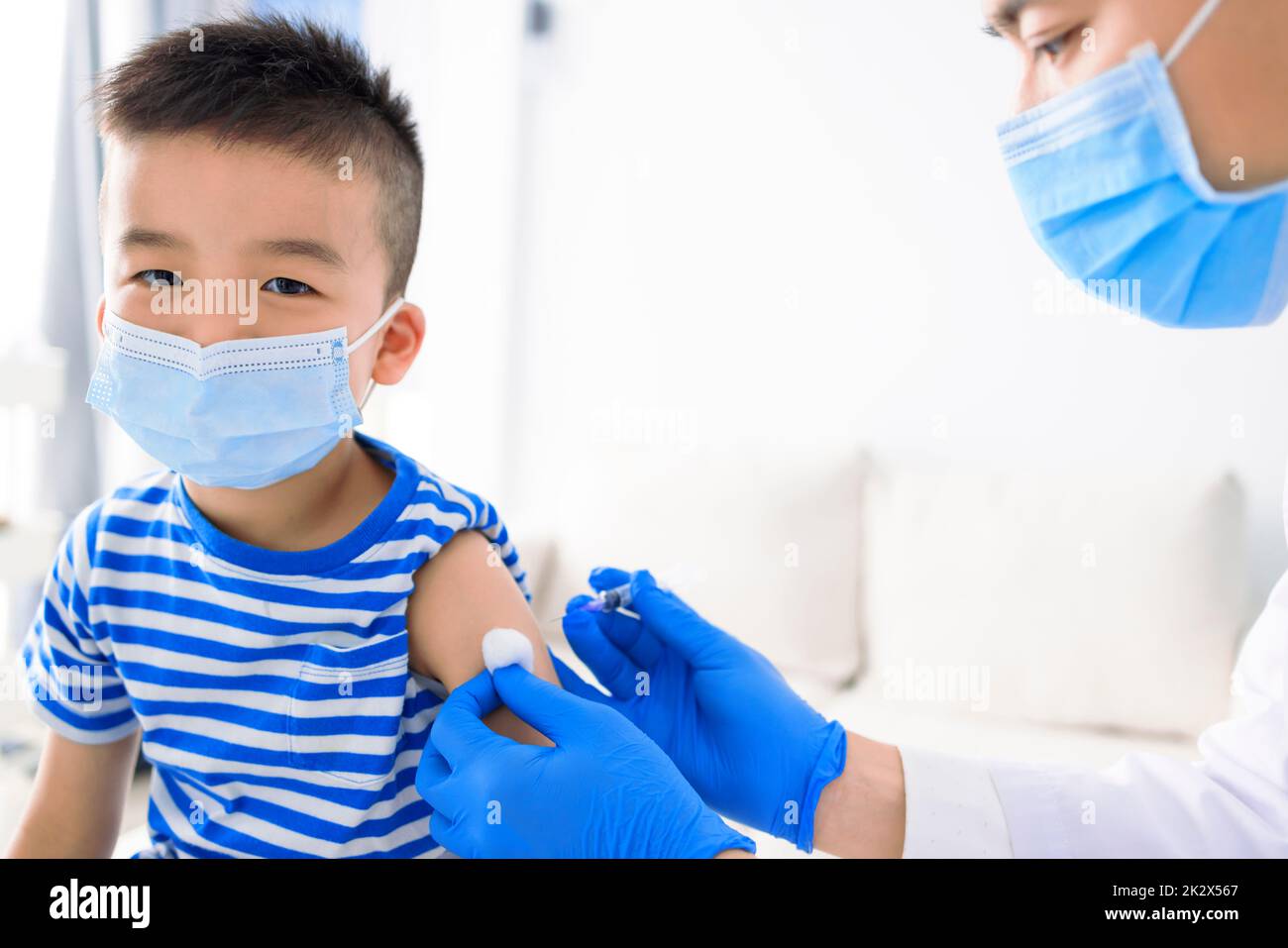 Medical Doctor injecting child with vaccine at clinic or hospital Stock Photo