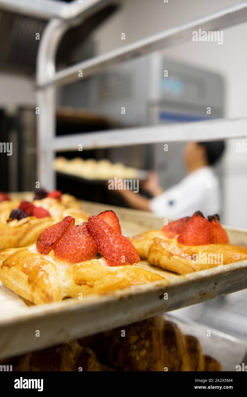 Close up fresh strawberry pastries on cooling rack in bakery kitchen