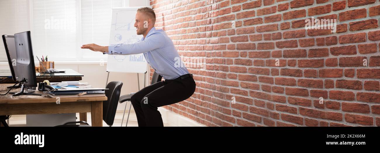 Businessman Doing Exercise In Office Stock Photo