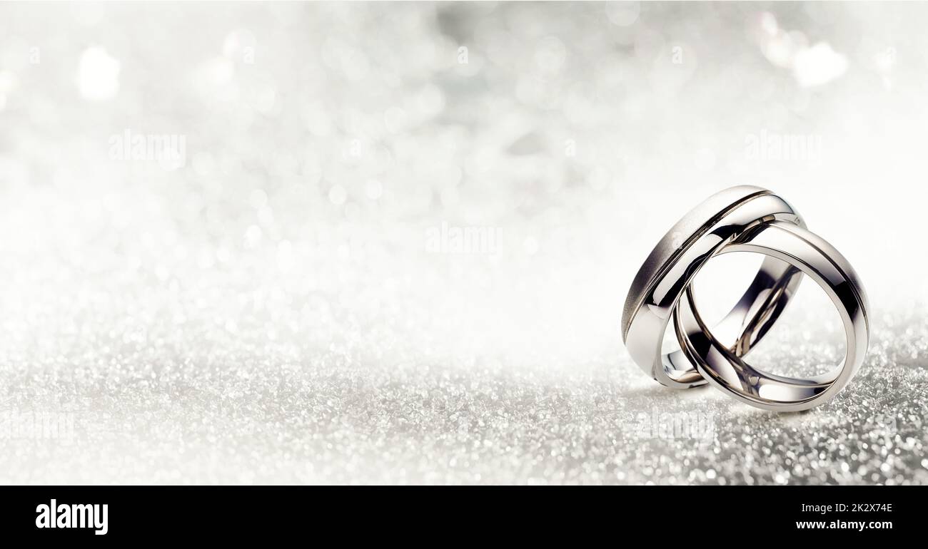 Shiny silver rings on white background with glowing glitter Stock Photo