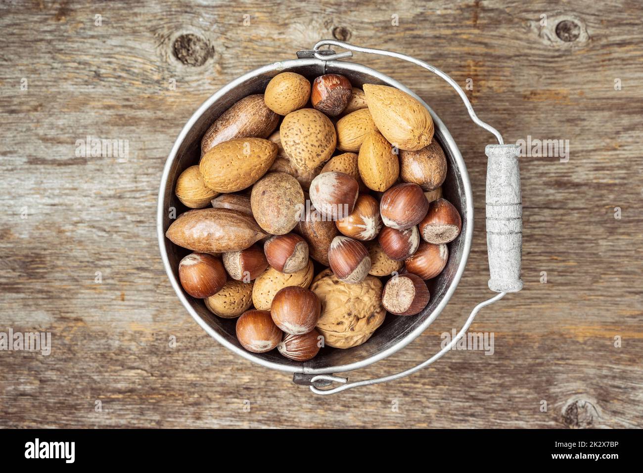 Old tin bucket with assortment of nuts in shells Stock Photo