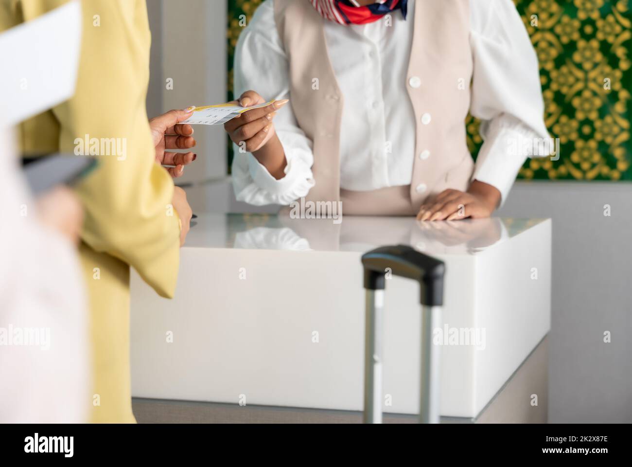 Woman traveler receive boarding pass ticket from female officer at airline check in service counter. Stock Photo