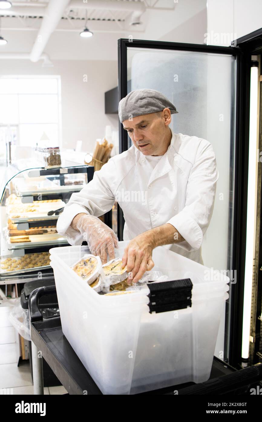Male baker placing pastries in bin inside bakery Stock Photo Alamy