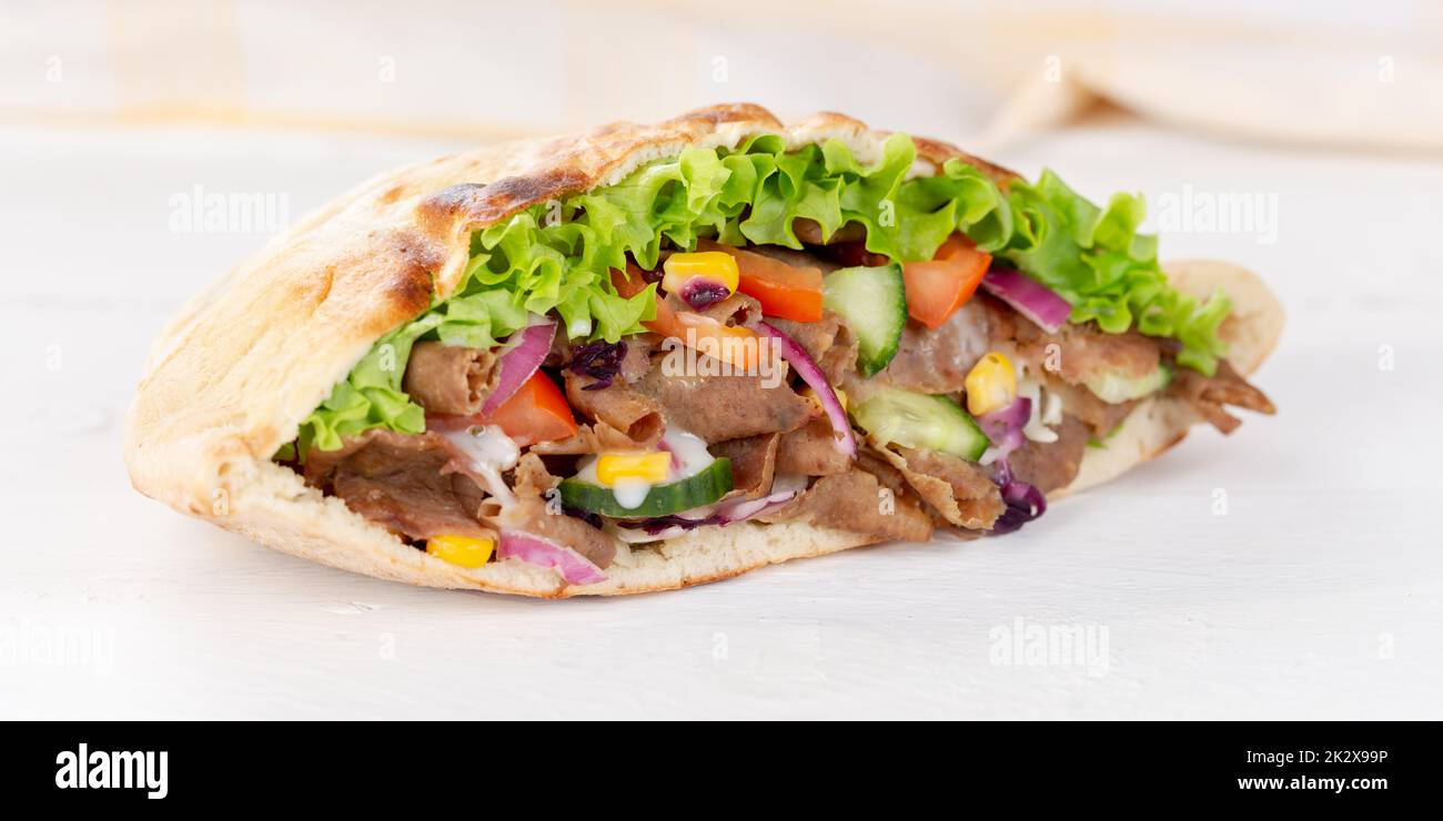 Döner Kebab Doner Kebap slice fast food in flatbread on a wooden board panorama sliced Stock Photo