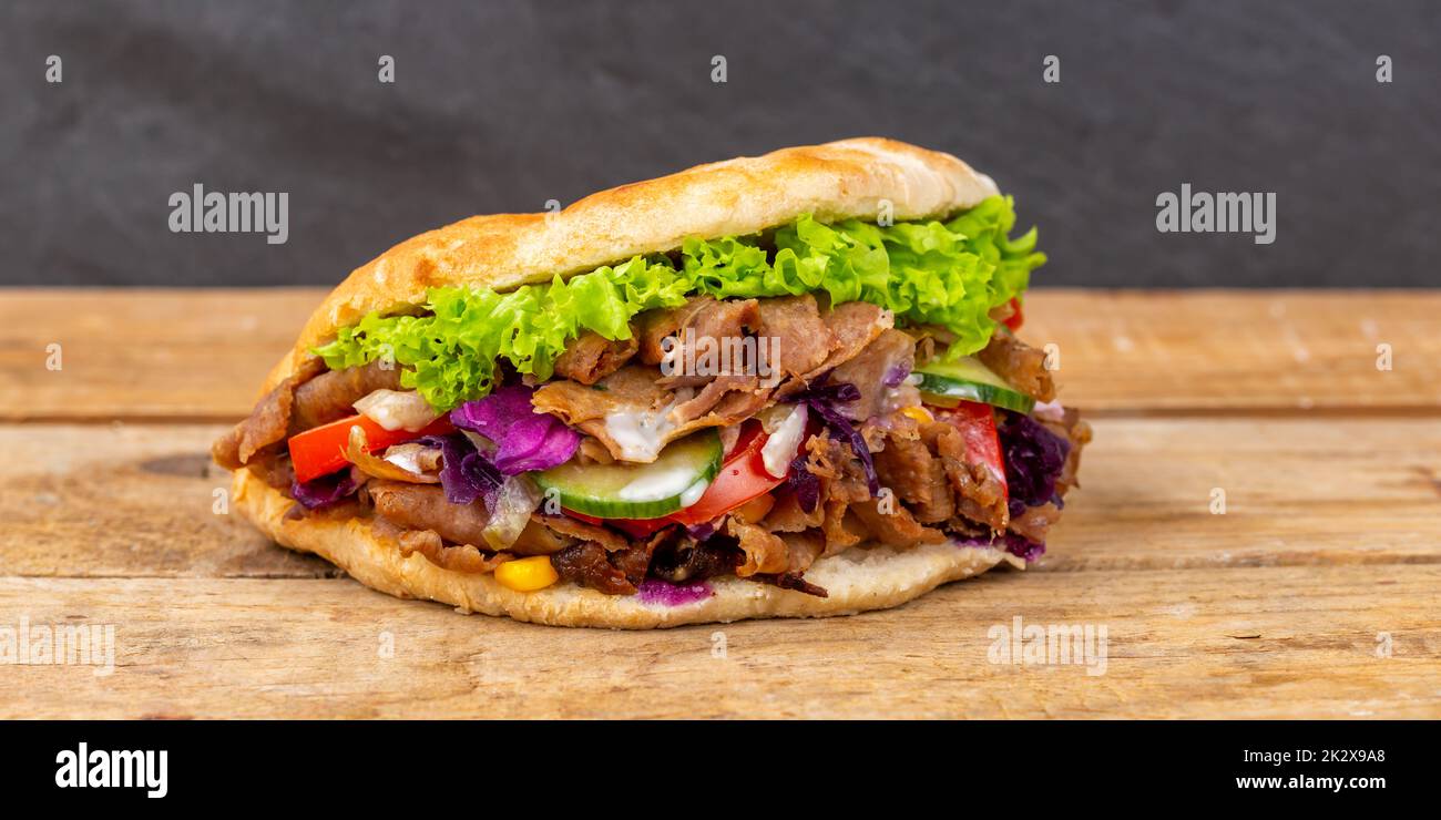 Döner Kebab Doner Kebap fast food in flatbread on a wooden board panorama snack Stock Photo