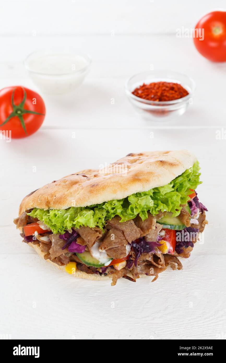 Döner Kebab Doner Kebap fast food in flatbread on a wooden board portrait format snack Stock Photo