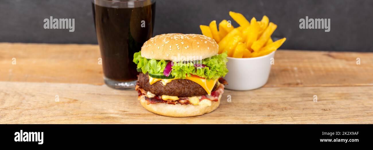 Hamburger Cheeseburger meal fastfood fast food with cola drink and French Fries on a wooden board panorama Stock Photo