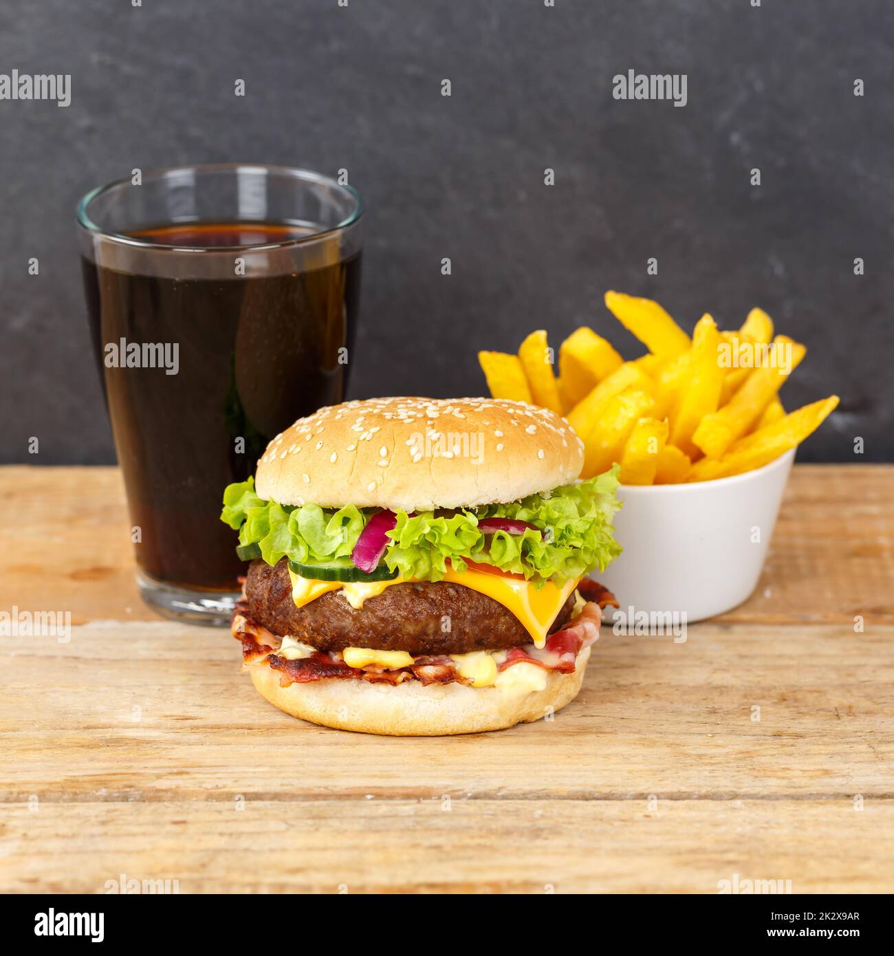 Hamburger Cheeseburger meal fastfood fast food with cola drink and French Fries on a wooden board square Stock Photo