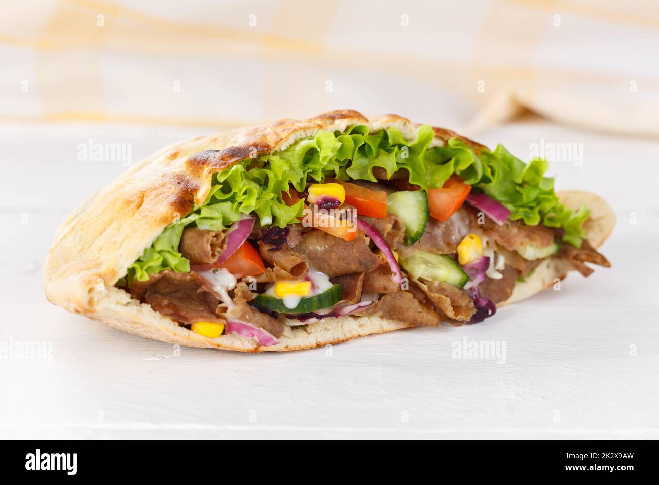 DÃ¶ner Kebab Doner Kebap slice fast food in flatbread on a wooden board Stock Photo