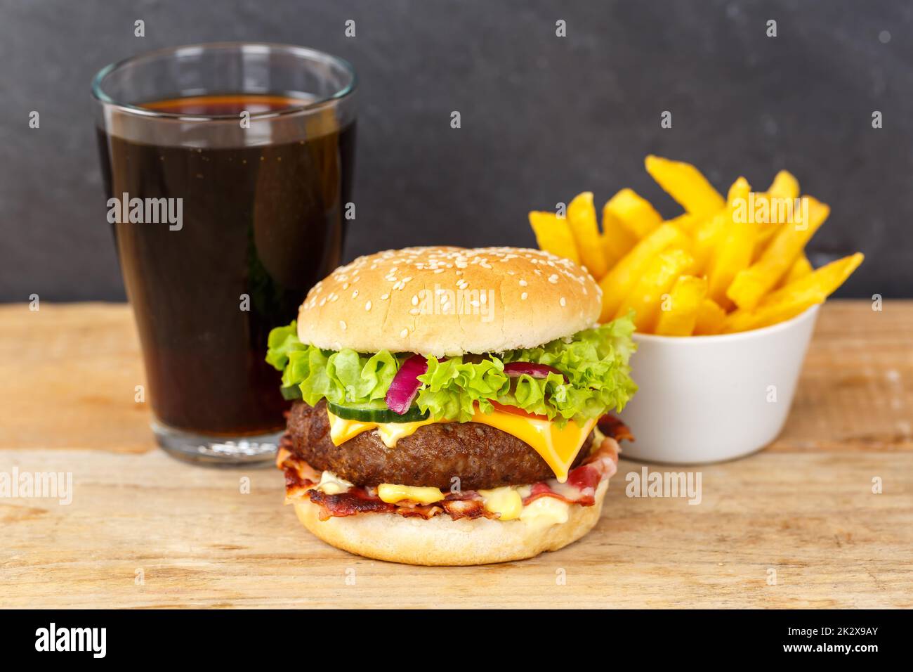 Hamburger Cheeseburger meal fastfood fast food with cola drink and French Fries on a wooden board Stock Photo