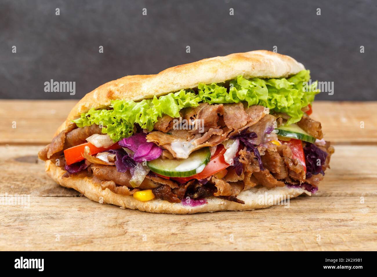 DÃ¶ner Kebab Doner Kebap fast food in flatbread on a wooden board Stock Photo